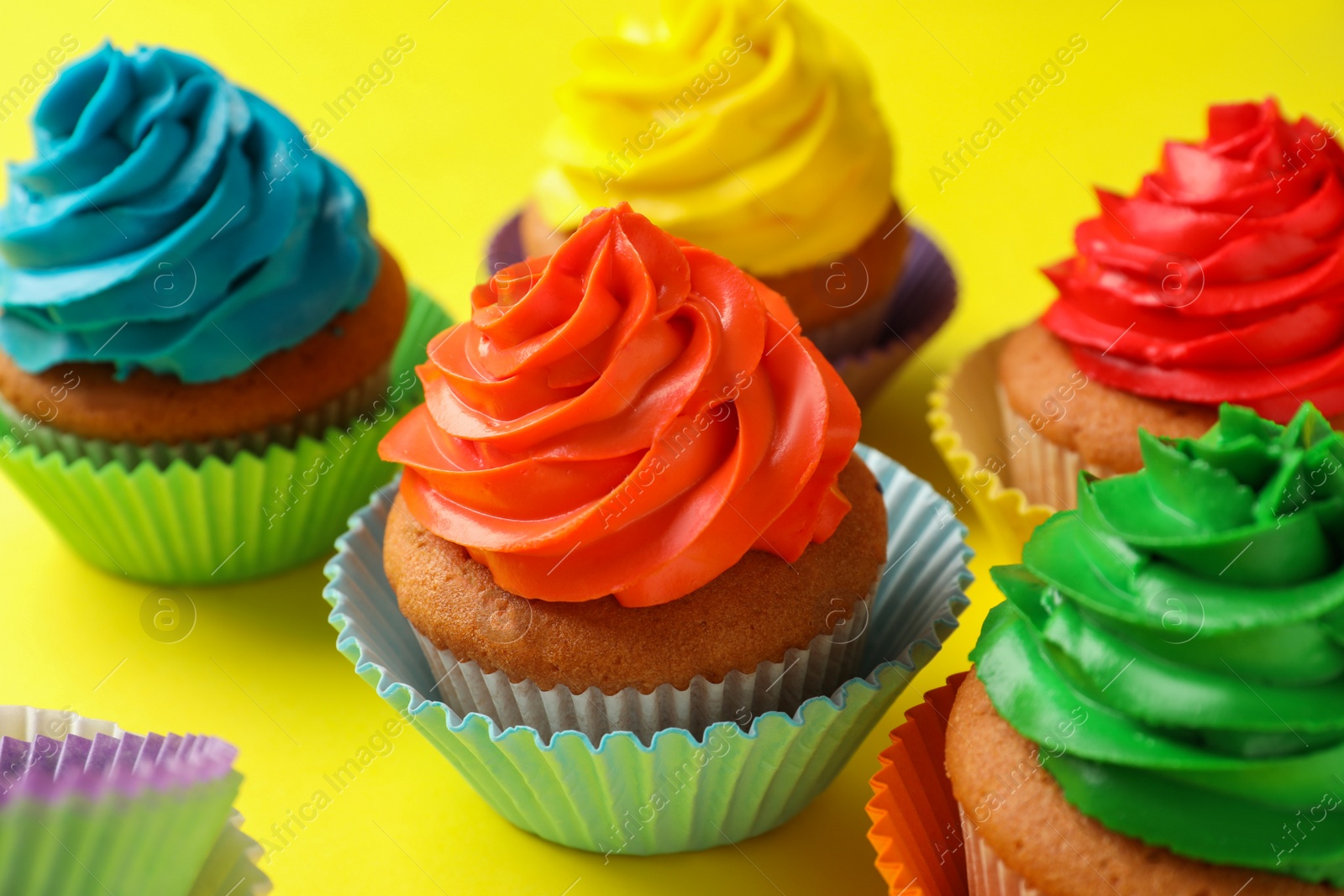 Photo of Delicious colorful cupcakes on yellow background, closeup