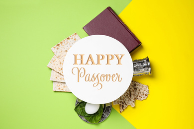 Symbolic Passover items and card on color background, flat lay. Pesah celebration