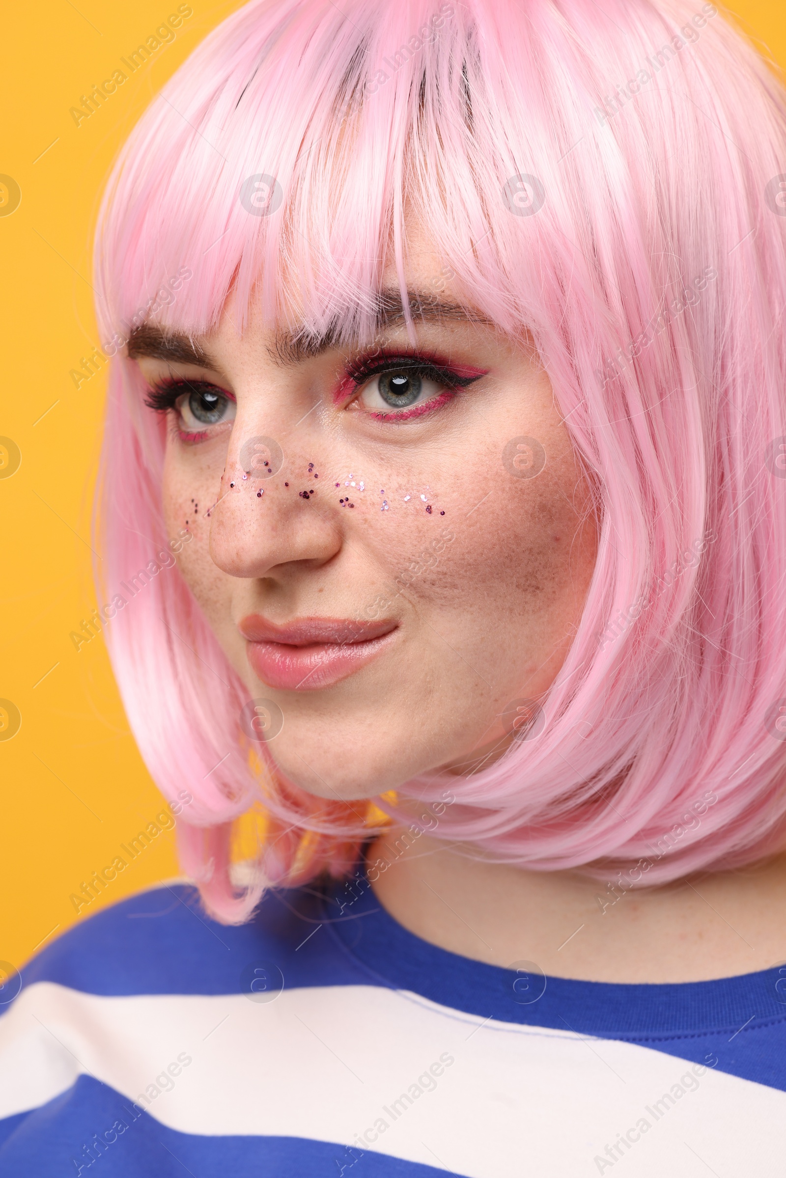 Photo of Beautiful woman with bright makeup and glitter freckles on yellow background, closeup