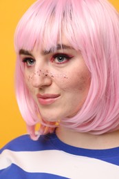Beautiful woman with bright makeup and glitter freckles on yellow background, closeup