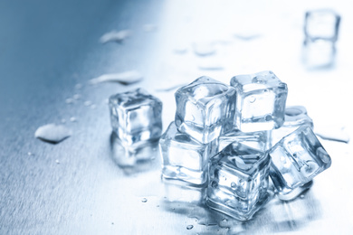 Photo of Crystal clear ice cubes with water drops on metal surface