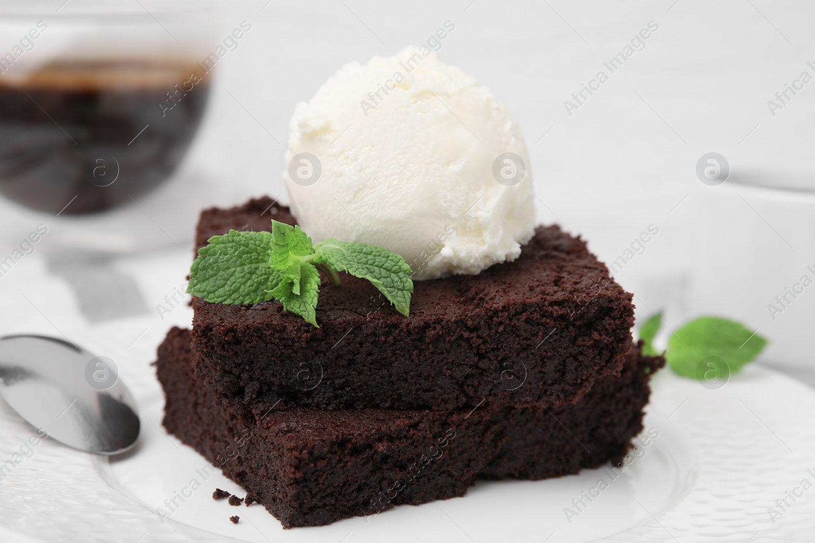 Photo of Tasty brownies served with ice cream and mint on plate, closeup