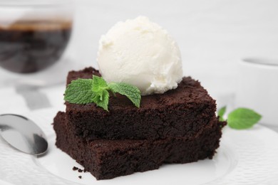 Tasty brownies served with ice cream and mint on plate, closeup