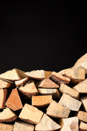 Photo of Cut firewood on black background. Space for text