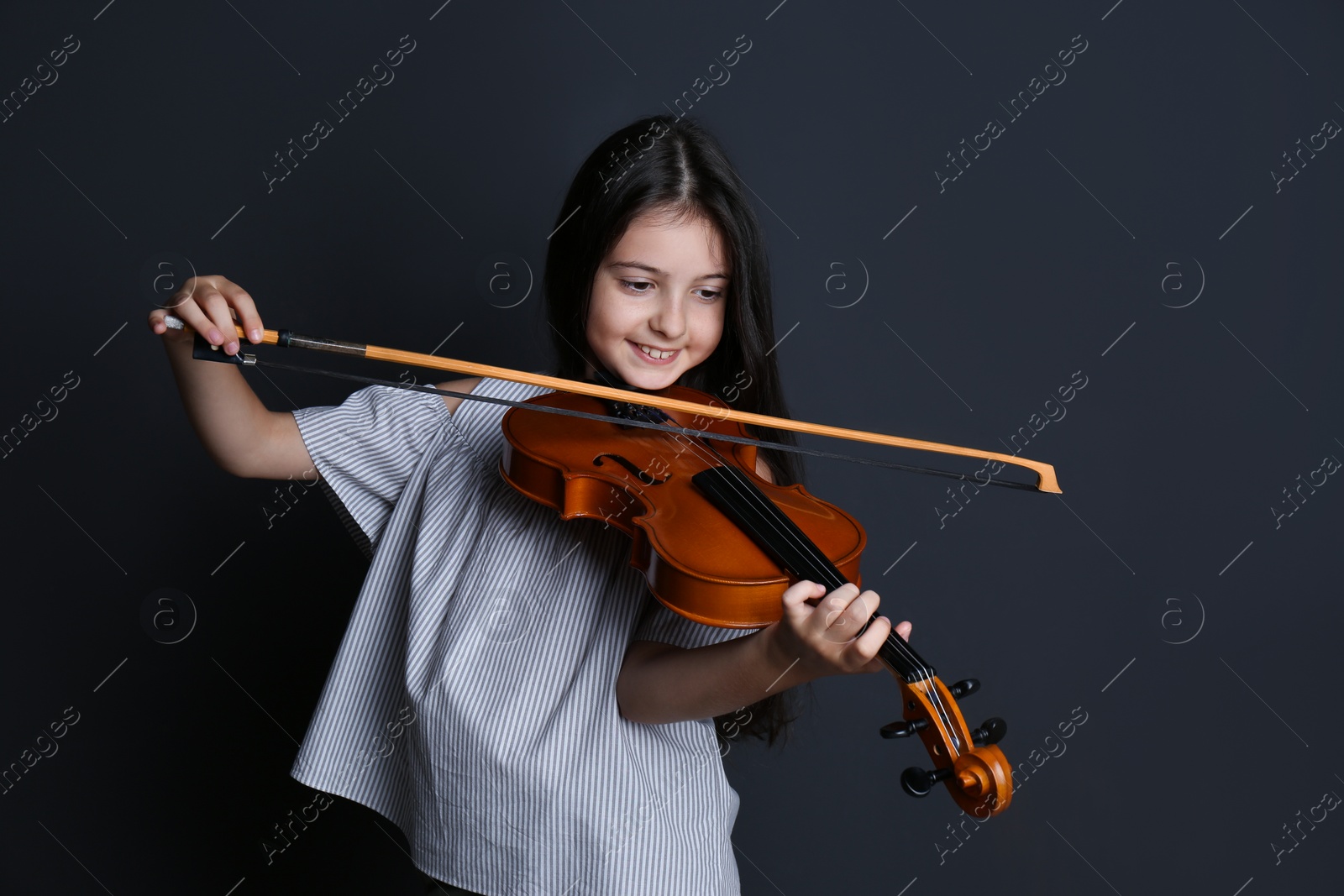 Photo of Preteen girl playing violin on black background