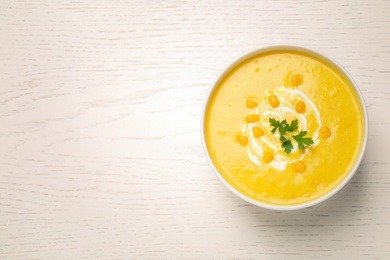 Delicious creamy corn soup served on white wooden table, top view. Space for text