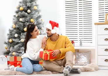 Happy young couple with Christmas gift at home