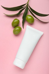 Tube of natural cream with olive essential oil on pink background, flat lay