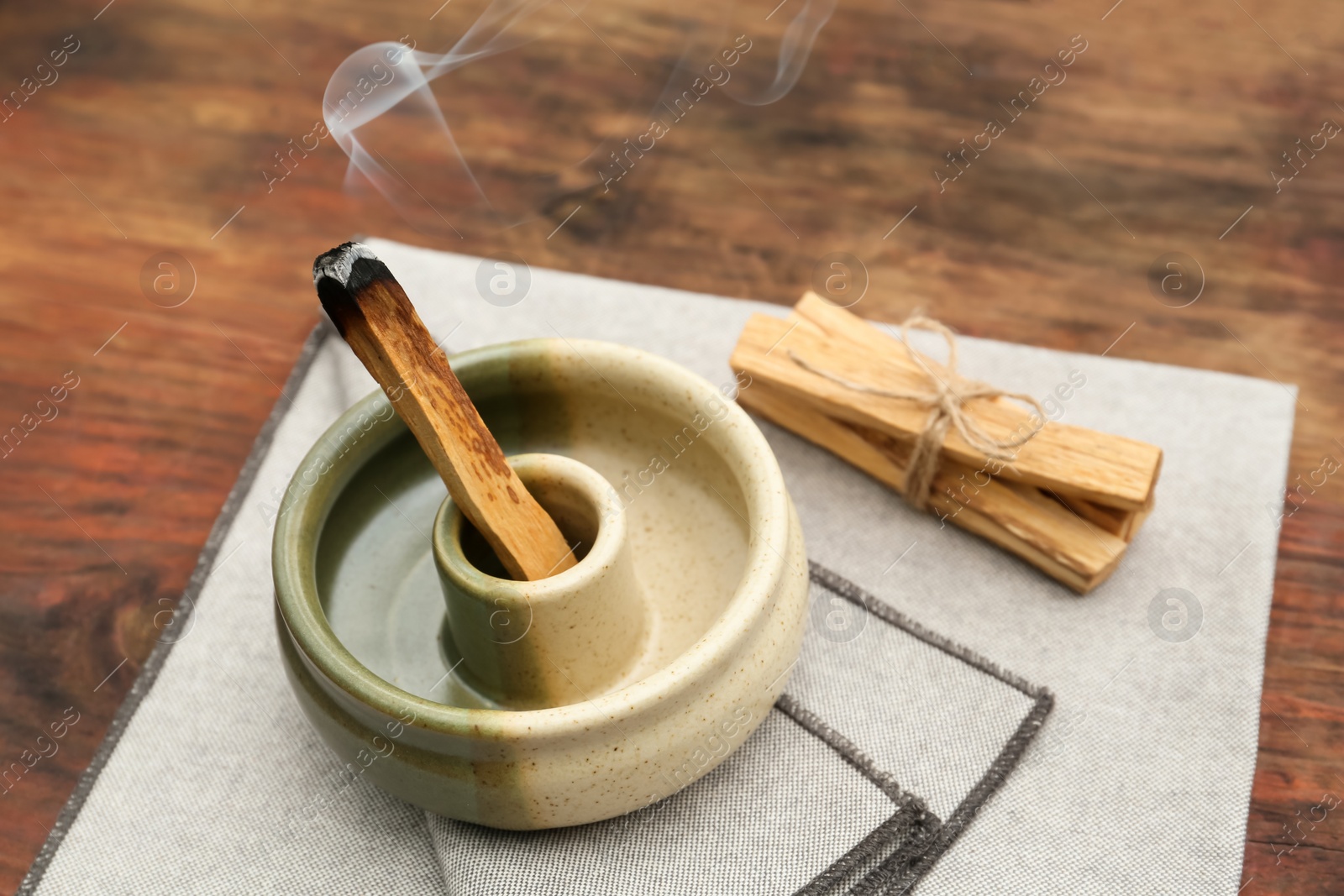 Photo of Palo Santo stick smoldering in holder on wooden table