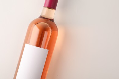 Photo of Bottle of tasty rose wine on white background, top view. Space for text