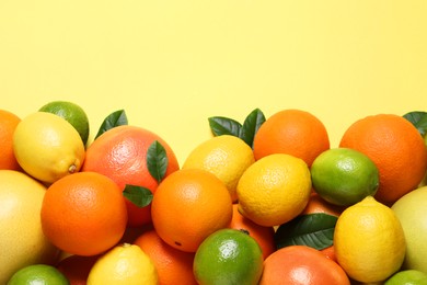 Photo of Different fresh citrus fruits and leaves on yellow background, flat lay. Space for text