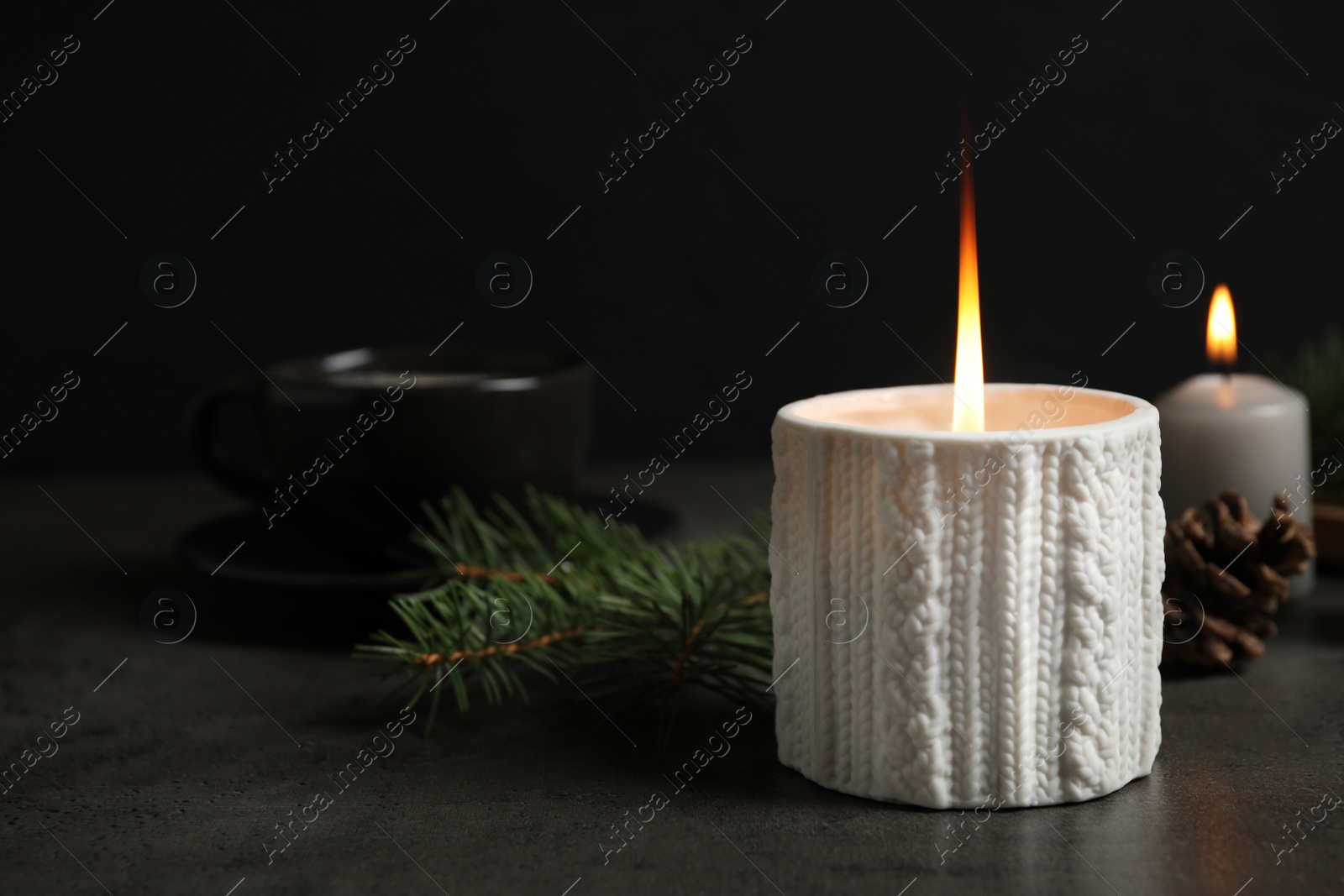 Photo of Candle and Christmas decor on dark grey table, space for text