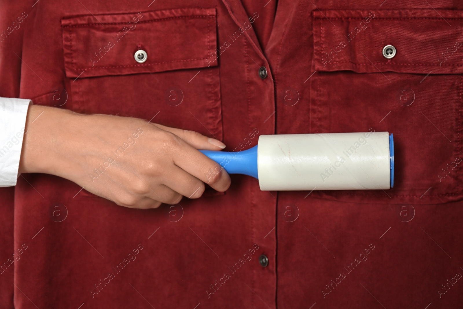 Photo of Woman cleaning red shirt with lint roller, closeup