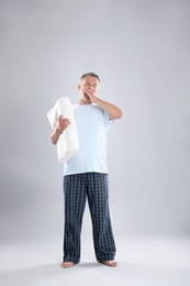 Photo of Man holding soft pillow on light background