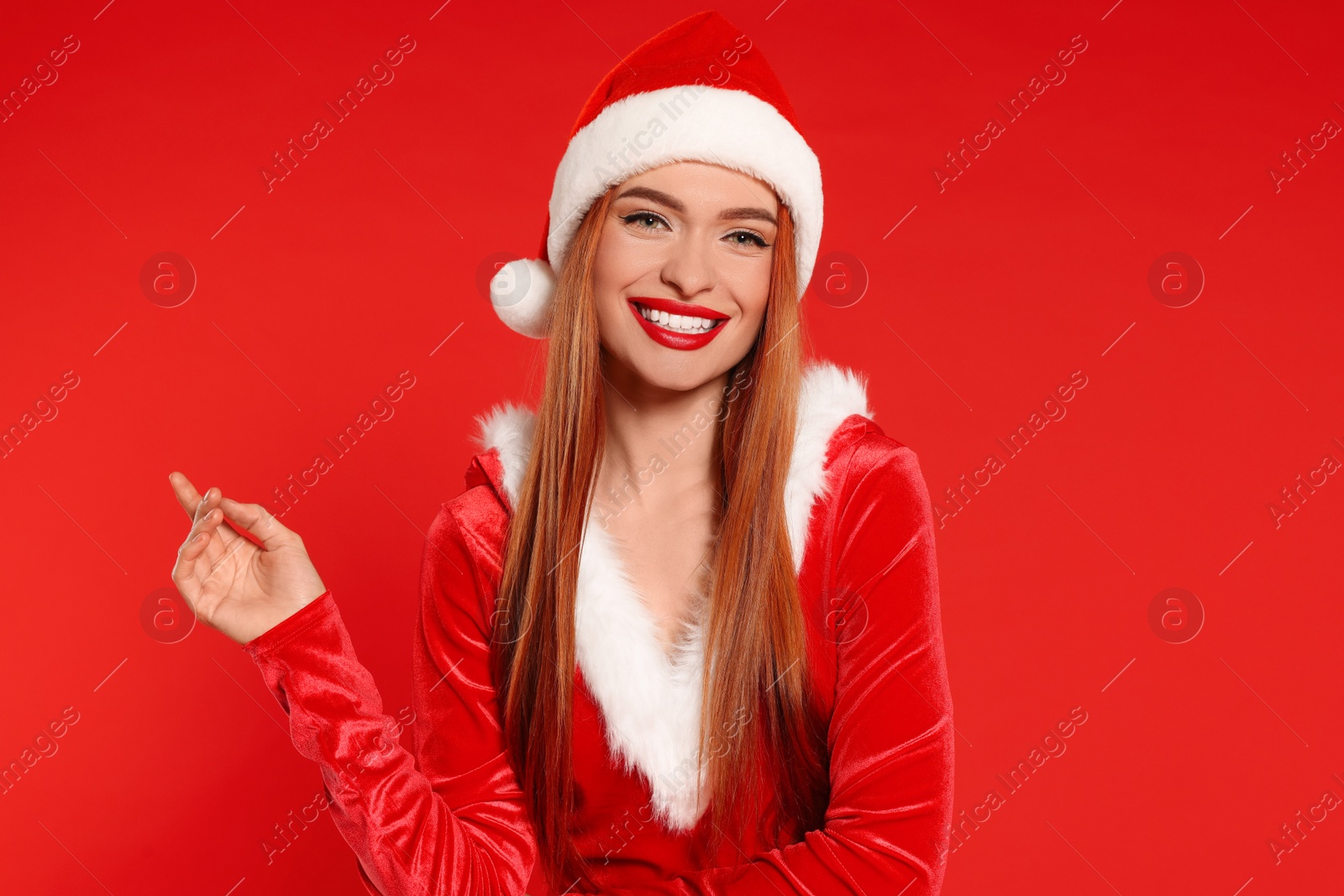 Photo of Young woman in Santa hat on red background. Christmas celebration