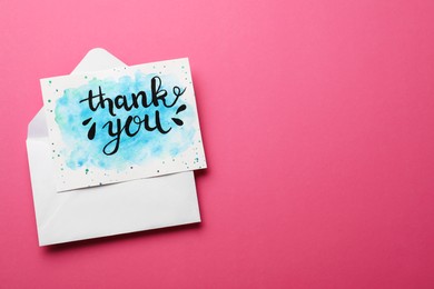 Photo of Envelope and card with phrase Thank You on pink background, top view. Space for text