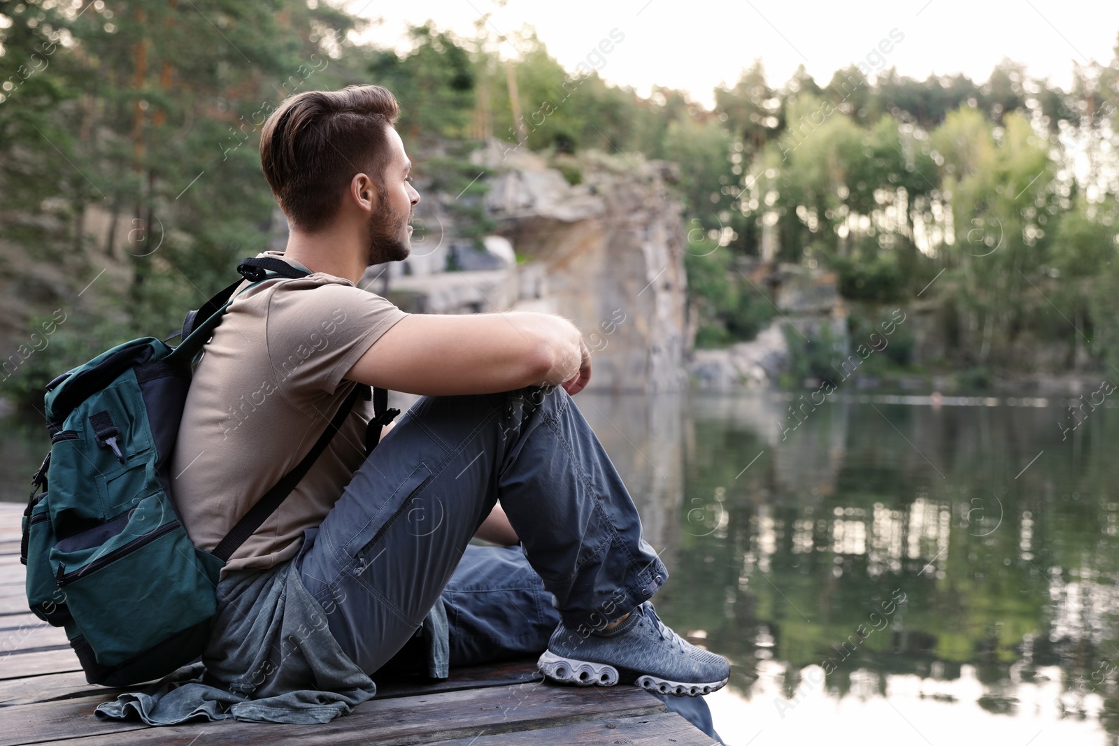 Photo of Young man on wooden pier near lake. Camping season