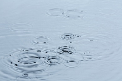 Photo of Rain drops falling down into puddle outdoors