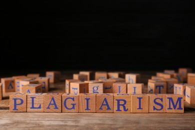 Photo of Wooden cubes with word Plagiarism on table, space for text