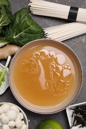 Photo of Cooking delicious ramen soup. Different ingredients on gray table, flat lay