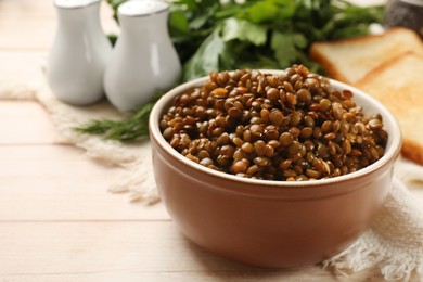 Photo of Delicious lentils in bowl served on white table, closeup. Space for text