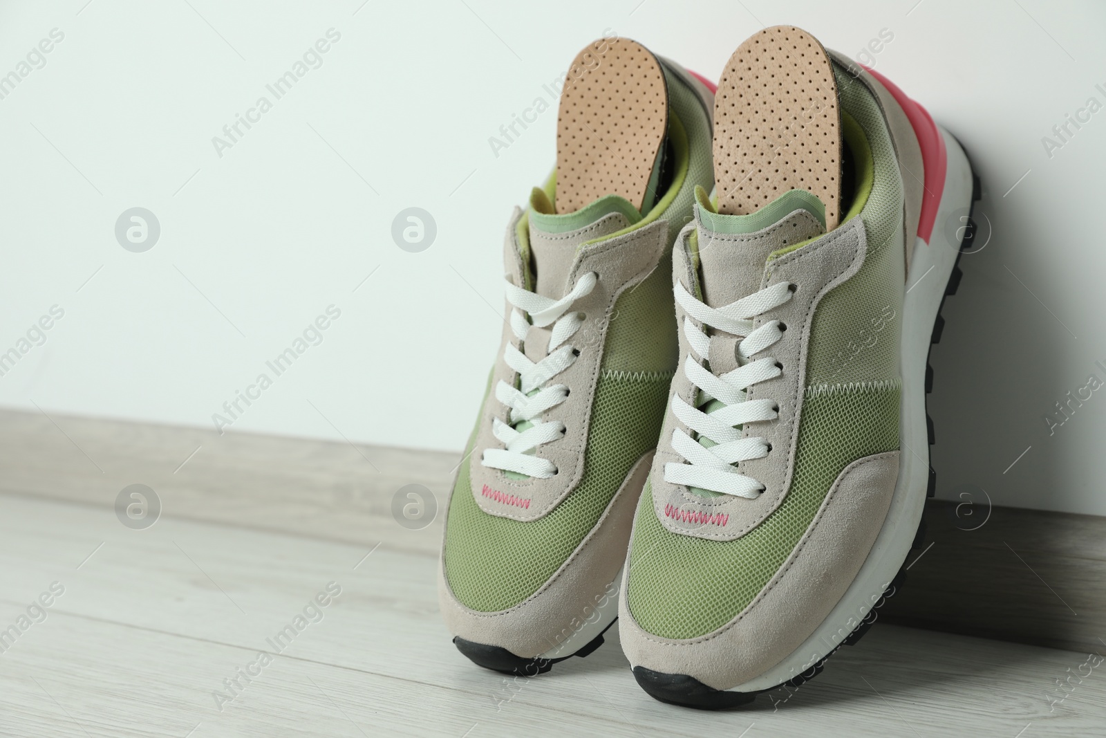Photo of Orthopedic insoles in shoes on floor, closeup. Space for text