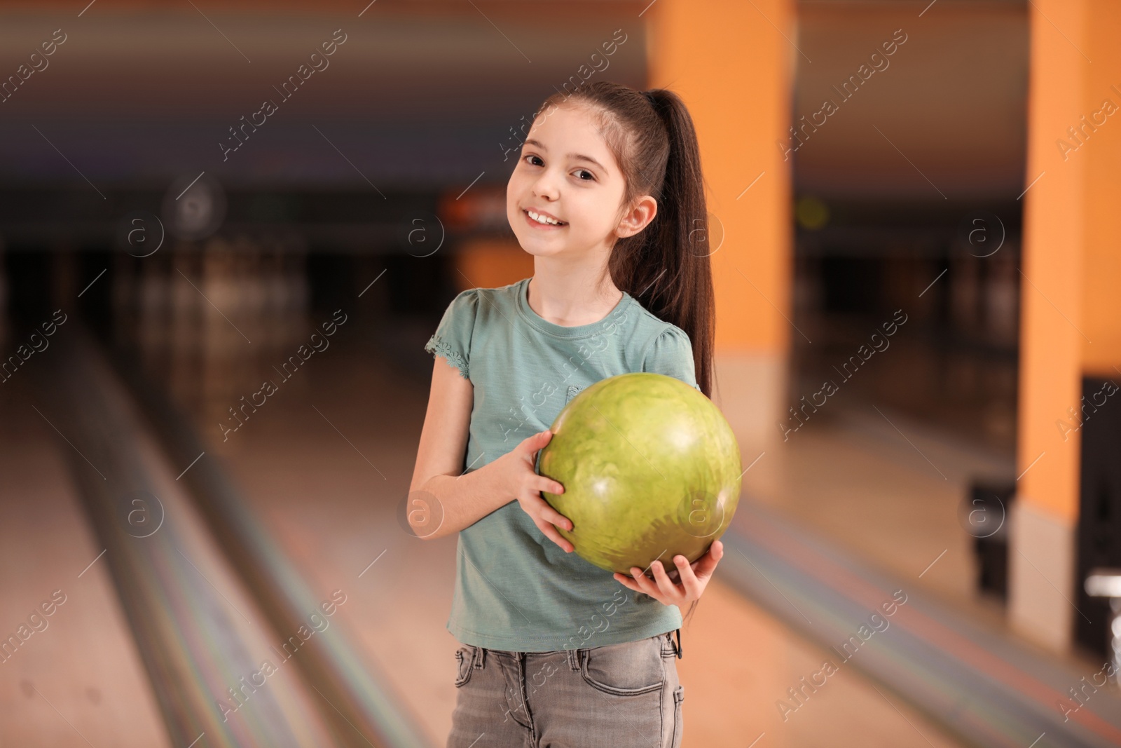 Photo of Little girl with ball in bowling club