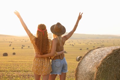 Photo of Hippie women near hay bale in field, back view