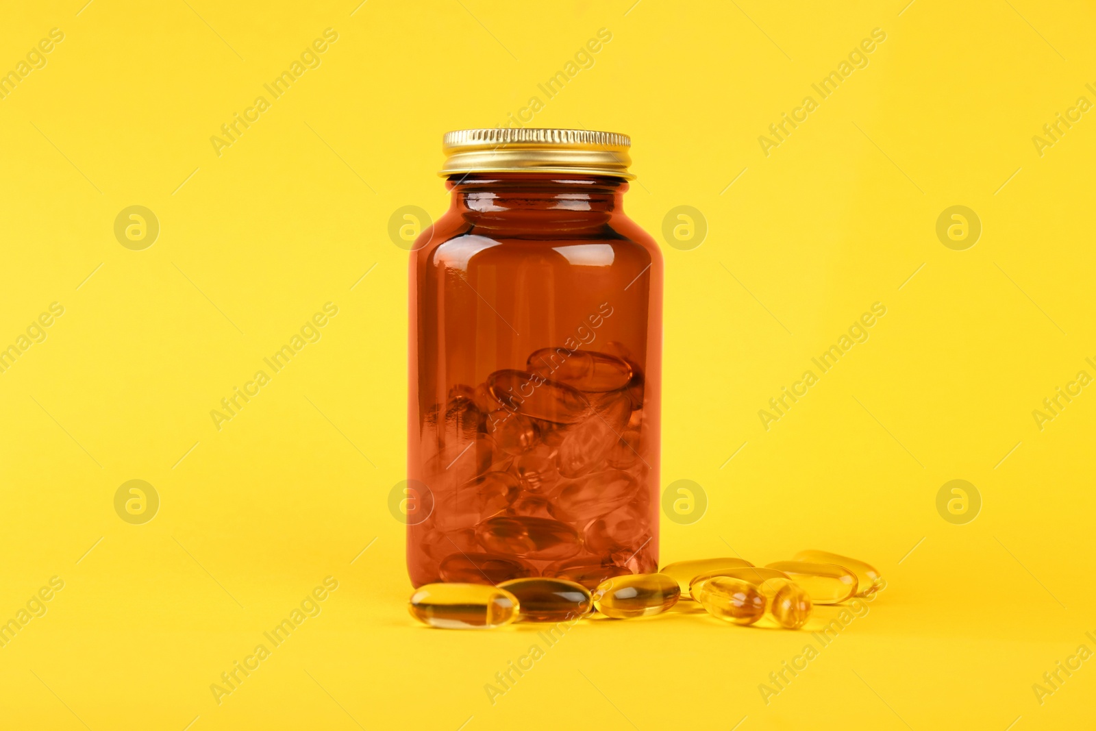 Photo of Jar with vitamin capsules on yellow background