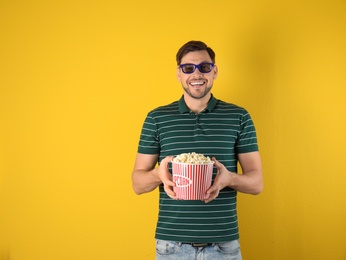 Man with 3D glasses and tasty popcorn on color background. Space for text