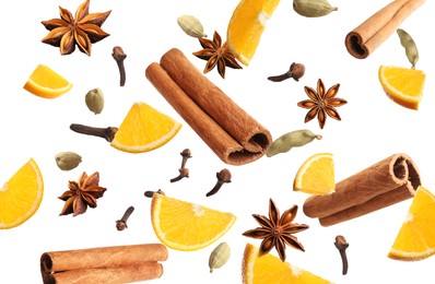 Pieces of fresh orange, aromatic anise stars, cinnamon, cloves and cardamom falling on white background