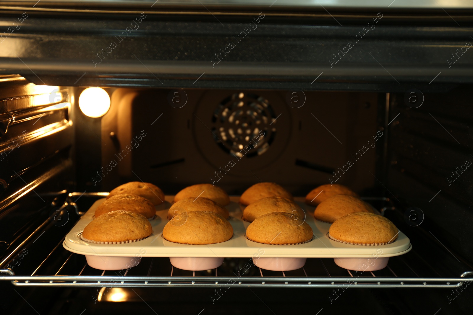 Photo of Baking pan with cupcakes in modern oven