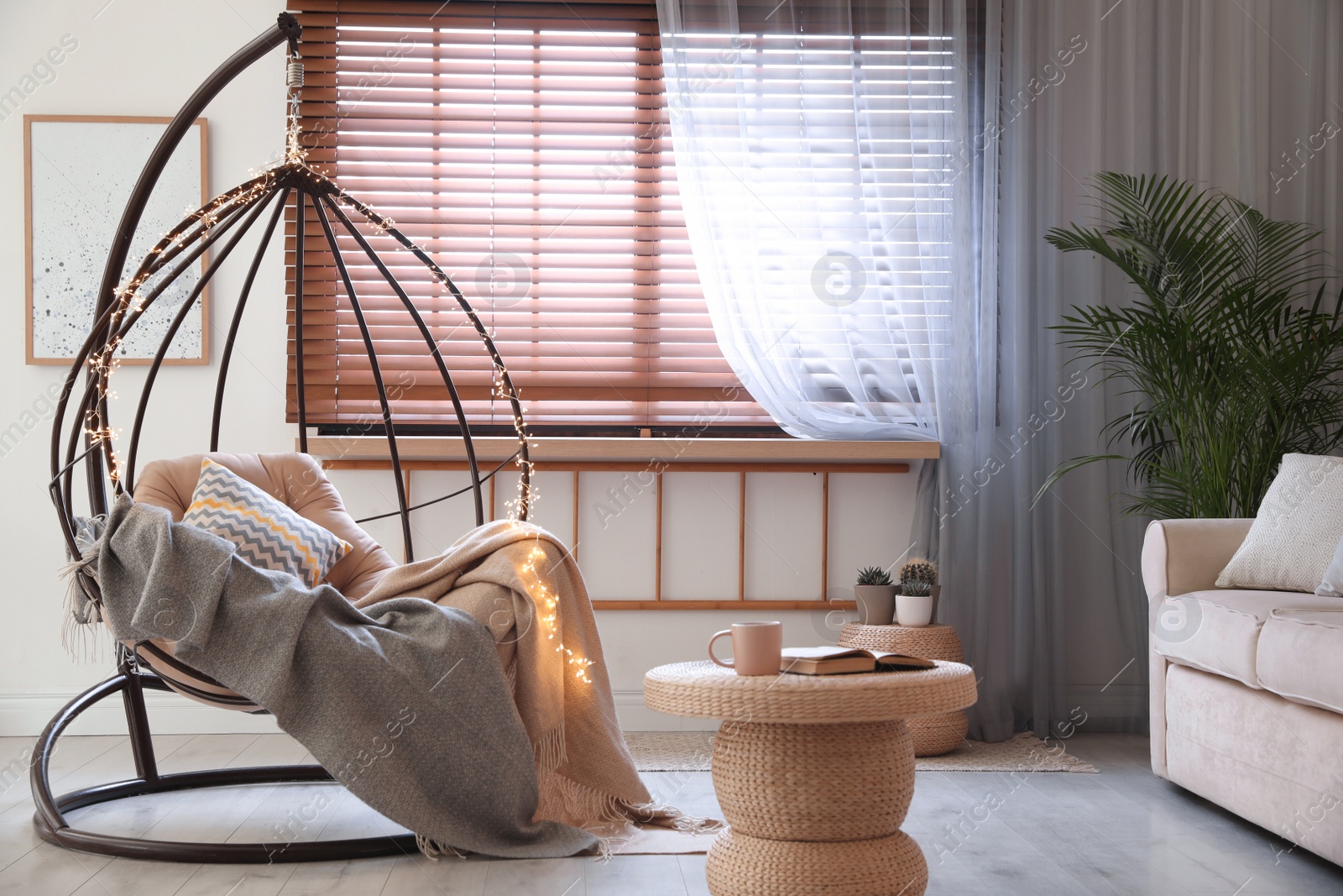 Photo of Cozy hanging chair with fairy lights in modern living room. Interior design