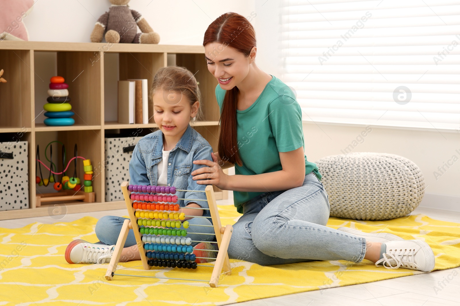 Photo of Happy mother and daughter playing with abacus on floor in room. Learning mathematics with fun