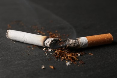 Photo of Burnt cigarette, tobacco and smoke on black table, closeup. No smoking concept