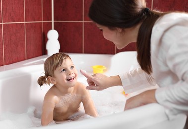 Photo of Mother with her little daughter spending time together in bathroom