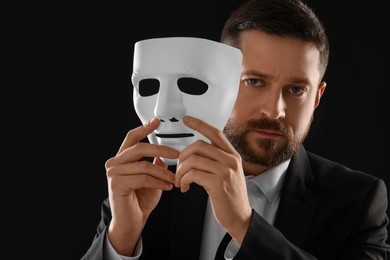 Multiple personality concept. Man with mask on black background