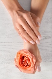 Photo of Closeup view of woman with rose at white wooden table. Spa treatment
