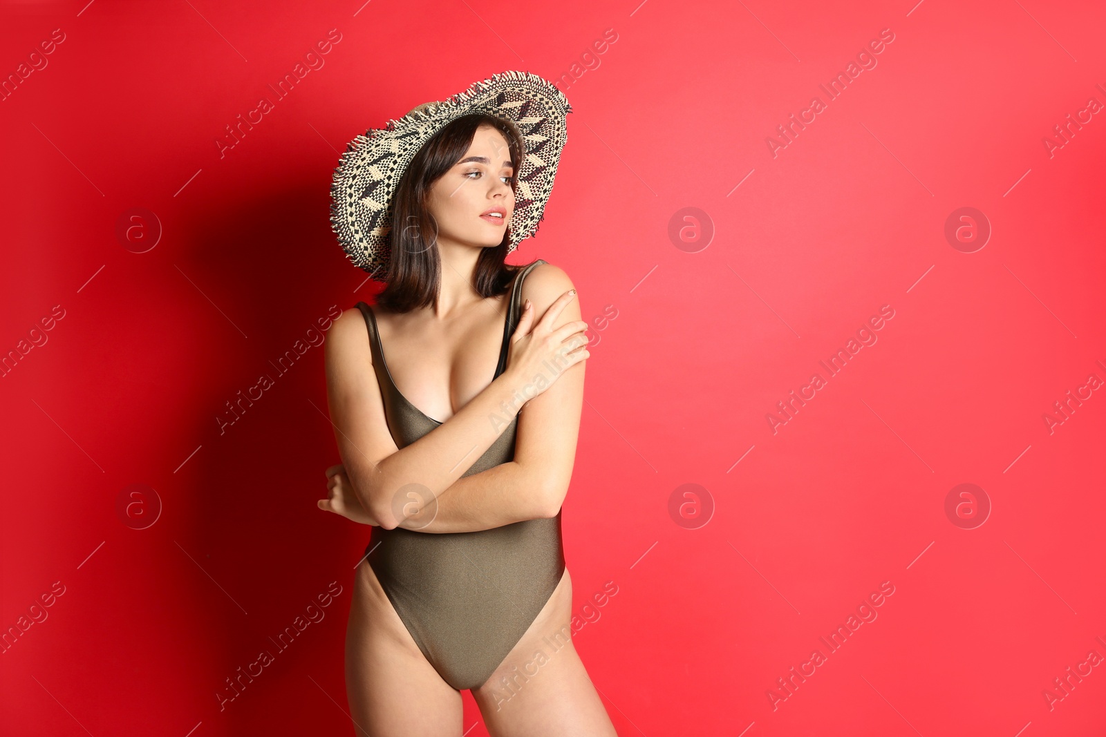 Photo of Beautiful woman in stylish swimsuit and hat on red background. Space for text