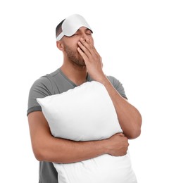 Photo of Tired man with pillow and sleep mask yawning on white background. Insomnia problem