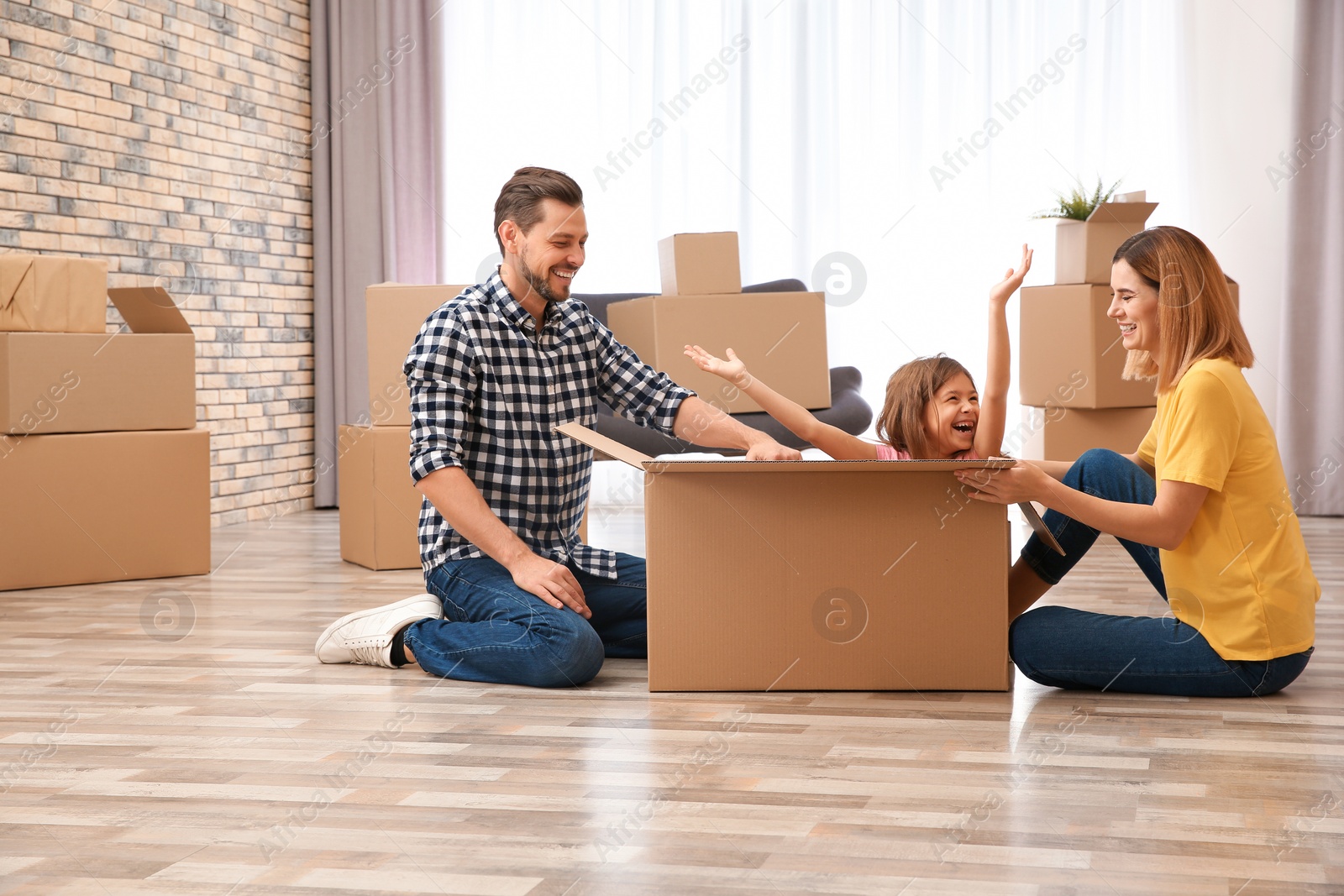 Photo of Happy family playing with cardboard box in their new house. Moving day