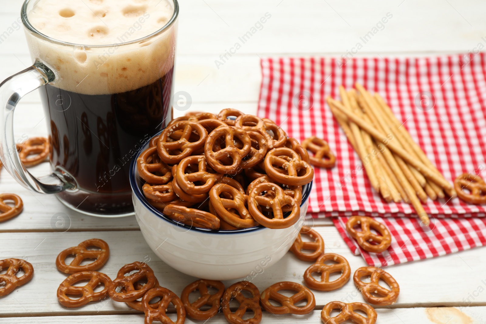 Photo of Delicious pretzel crackers and mug of beer on white wooden table