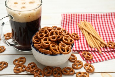 Delicious pretzel crackers and mug of beer on white wooden table