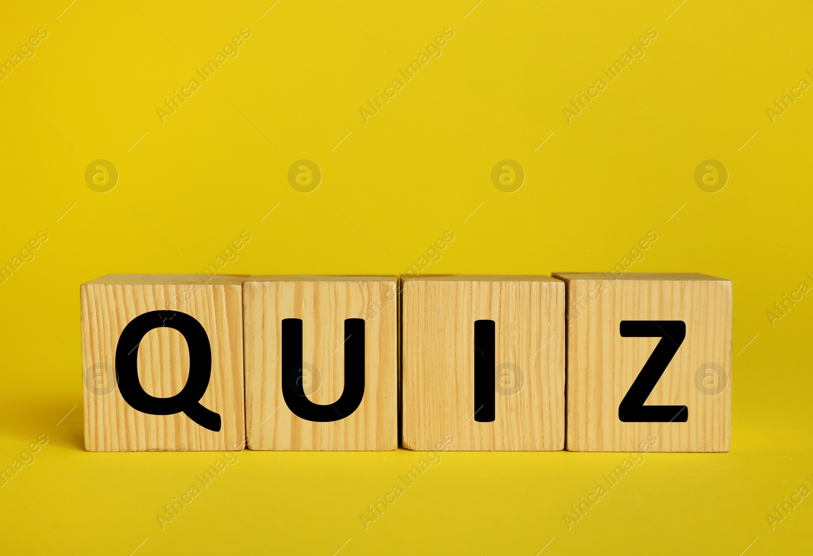 Photo of Wooden cubes with word Quiz on yellow background. Space for text