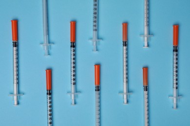 Photo of Disposable syringes on light blue background, flat lay