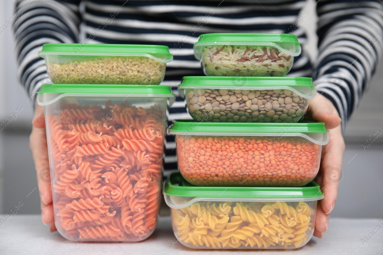 Photo of Woman with plastic containers filled of food products at light table indoors, closeup