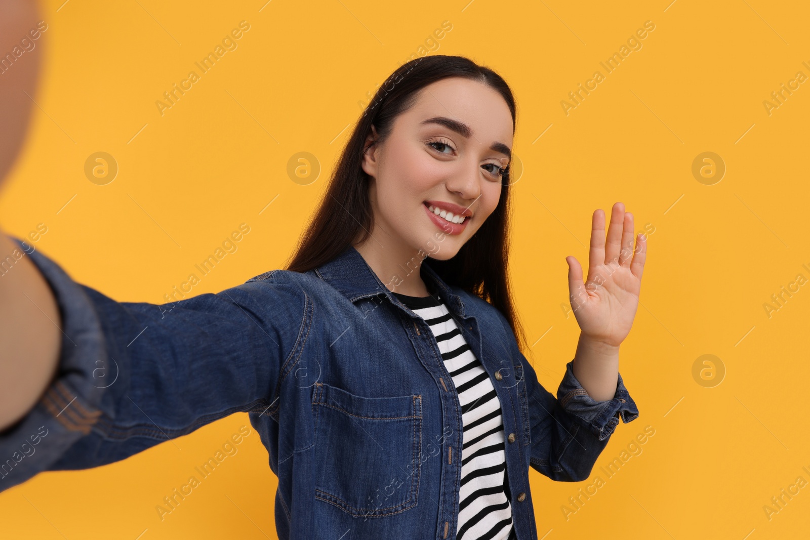 Photo of Smiling young woman taking selfie on yellow background