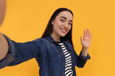 Photo of Smiling young woman taking selfie on yellow background
