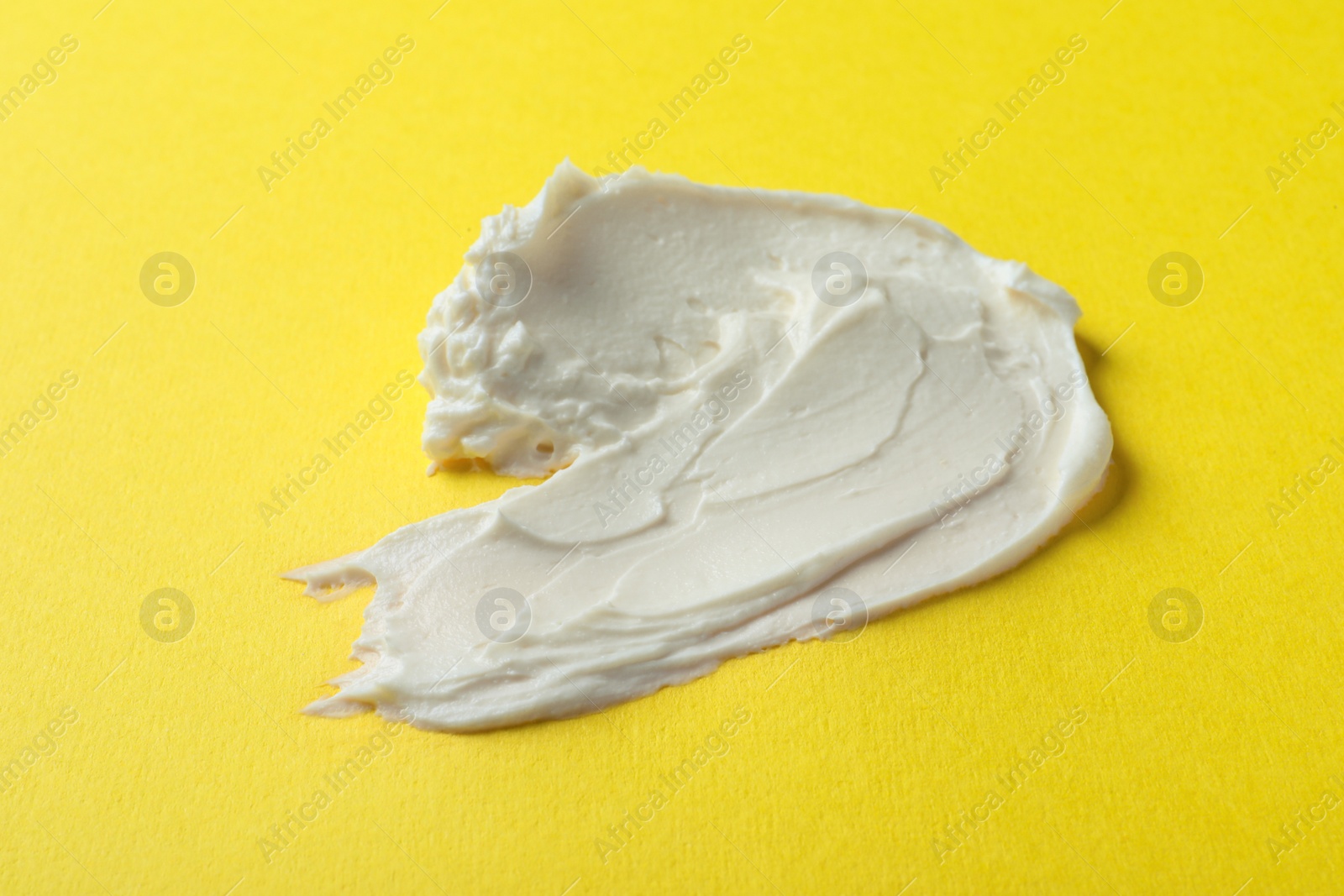 Photo of Smear of delicious cream cheese on yellow background