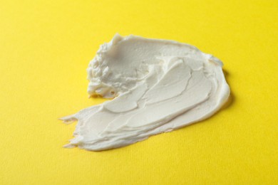 Photo of Smear of delicious cream cheese on yellow background